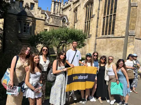 Cambridge'de tarihi kolej duvarının önünde pankartlı grup
