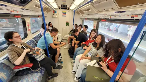 Metro vagonunda yan yana oturan öğrenciler